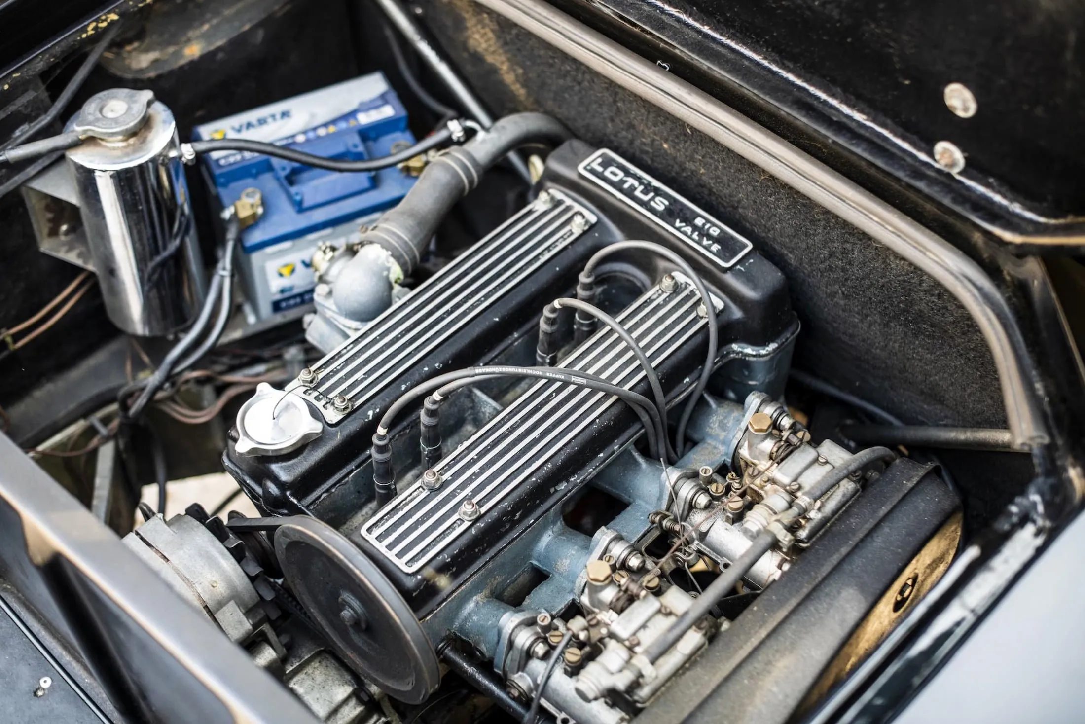 A Lotus–Ford twin-cam engine sitting in an engine bay, its cam covers reading 'Lotus Big Valve', fed by twin Weber carburettors.